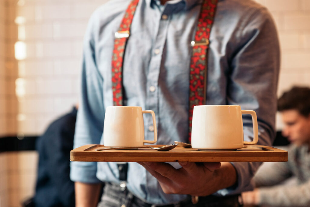 Waiter carrying a tray with two coffees