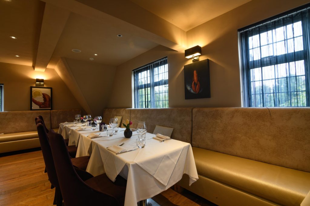 Long table laid for a group in a private dining room with banquette seating at The Gables