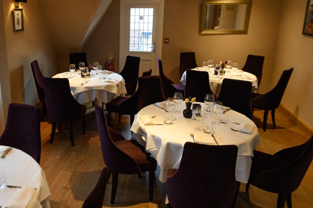 Upstairs dining room with round tables and purple velvet chairs at The Gables
