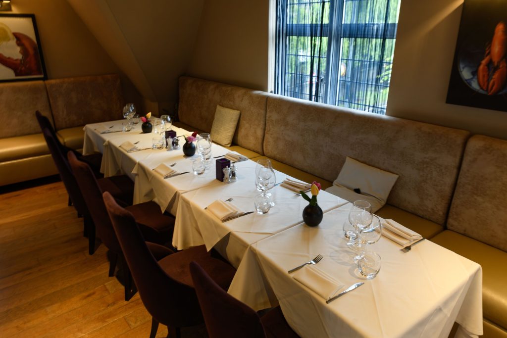 Long table laid for a group beside banquette seating in an upstairs room at The Gables