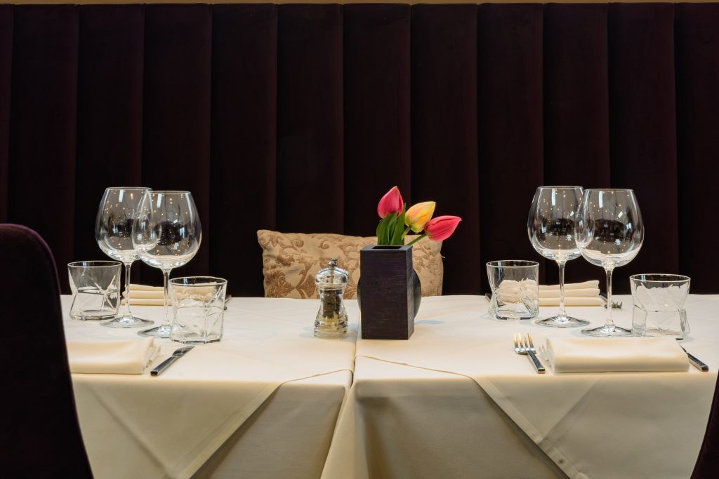 Table for two laid with white linen, wine glasses and tulips at The Gables