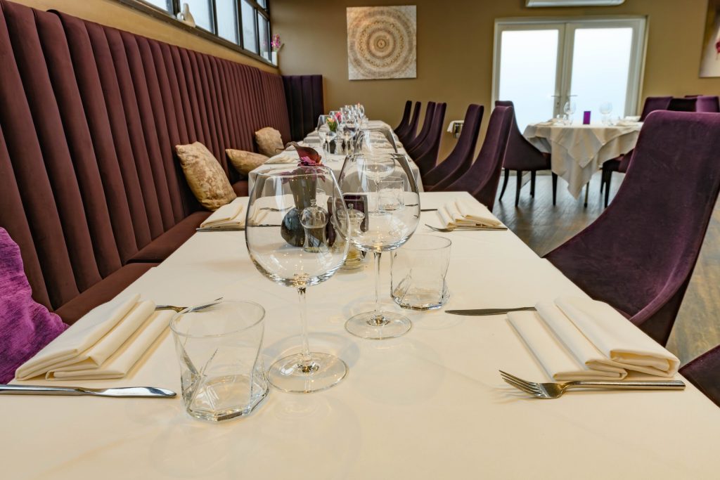 Long table laid beside purple banquette seating in the restaurant at The Gables