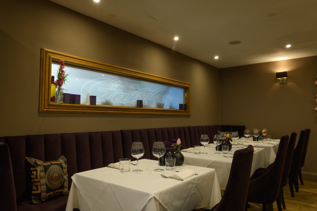 Dining room with banquette seating and gilt-framed mirror at The Gables