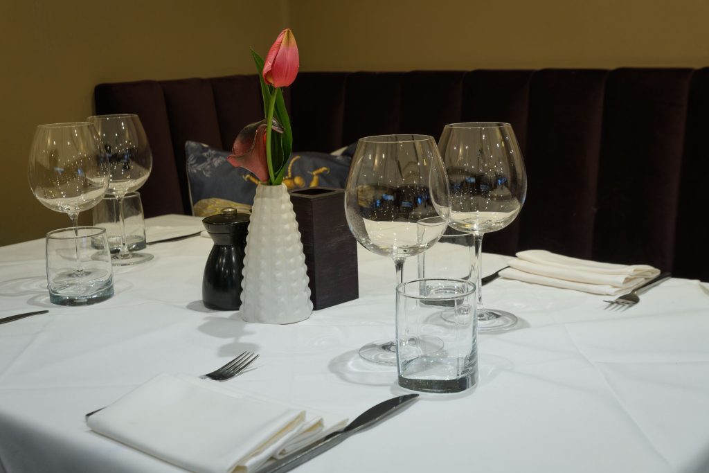 Table setting with wine glasses and a pink tulip at The Gables