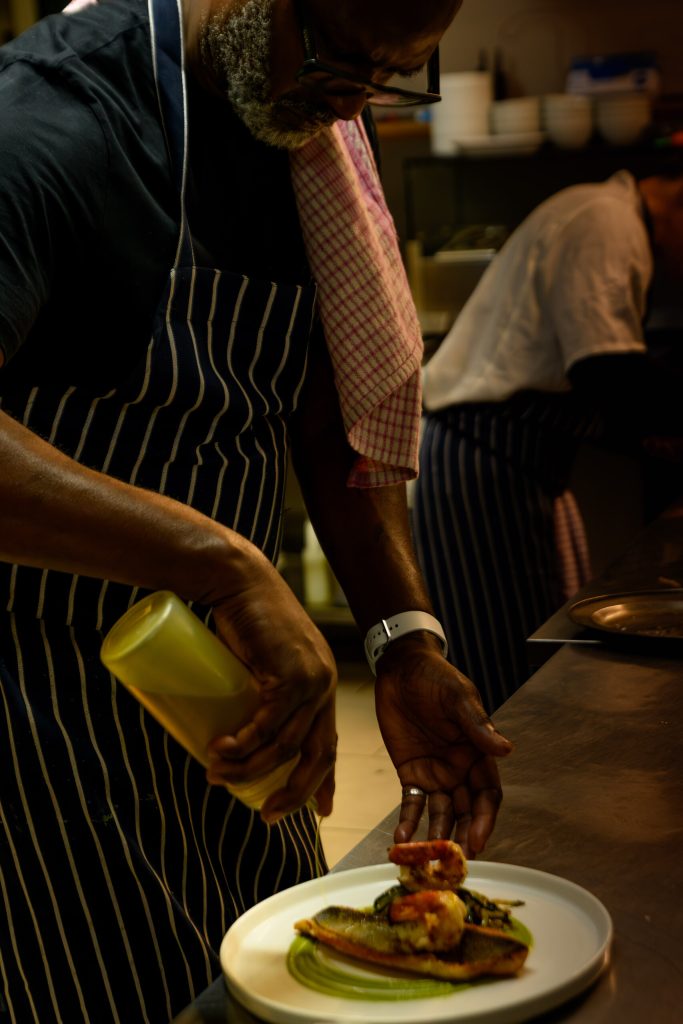 Chef finishing a plated dish in the kitchen at The Gables